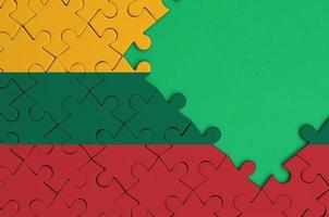 Die litauische Flagge ist auf einem fertigen Puzzle mit freiem Platz für grüne Kopien auf der rechten Seite abgebildet foto