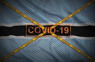 botswana-flagge und covid-19-stempel mit orangefarbenem quarantäne-grenzbandkreuz. Coronavirus- oder 2019-ncov-Viruskonzept foto