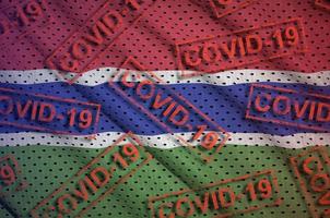 gambia-flagge und viele rote covid-19-stempel. Coronavirus- oder 2019-ncov-Viruskonzept foto