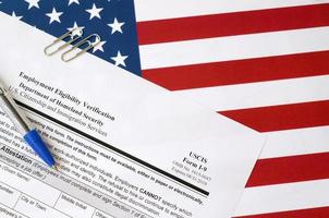 Das leere Formular zur Überprüfung der i-9-Beschäftigungsberechtigung liegt auf der Flagge der Vereinigten Staaten mit blauem Stift vom Ministerium für innere Sicherheit foto