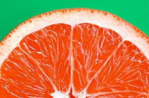 Draufsicht auf eine Grapefruitscheibe auf hellem Hintergrund in grüner Farbe. ein gesättigtes Zitrustexturbild foto