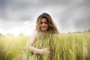 schöne Dame, die Ähren des Weizens im Freien umarmend foto