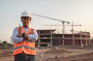 asiatischer ingenieur, der auf der baustelle eines großen bauprojekts arbeitet, thailänder, machen überstunden auf der baustelle foto