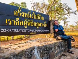 asiatischer reisender mit glückwunsch an den phukradueng-erobererzeichen auf der spitze des phu kradueng-berg-nationalparks in der stadt loei thailand. phu kradueng-nationalpark das berühmte reiseziel foto