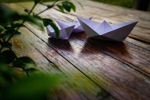 Origami, weißes Papierboot isoliert auf einem Holzboden. Papierboote bedeuten Gehen. Gefühl der Freiheitsführung foto