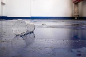 Plastikglas mit einem Getränk fiel während des Stampfens auf das Deck des Schiffes und verschüttete es. Untersicht. foto