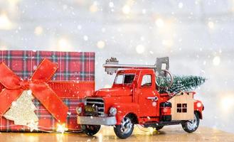 Rotes Retro-Auto mit einem Weihnachtsbaum schmückt mit dem Hausschlüssel im Pickup-Truck zu Weihnachten. Hauskauf, Umzug, Hypothek, Darlehen, Immobilien, Feststimmung, Neujahr foto