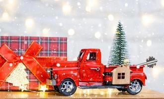 Rotes Retro-Auto mit einem Weihnachtsbaum schmückt mit dem Hausschlüssel im Pickup-Truck zu Weihnachten. Hauskauf, Umzug, Hypothek, Darlehen, Immobilien, Feststimmung, Neujahr foto