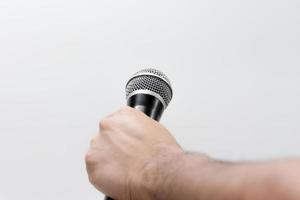 Hand hält ein Mikrofon isoliert auf weißem Hintergrund foto