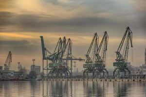 am abend die silhouette von hafenkränen. bereit, container von frachtschiffen zu laden. foto