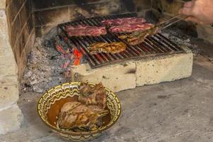 Braten von frischem Fleisch im Kamin und Schüssel mit Steak. grillen foto