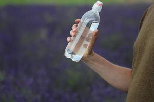 Hand, die eine Flasche Wasser hält foto