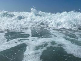 Wunderschönes Meer mit Wellen, die warmes, funkelndes, klares blaues Wasser in einem warmen, tropischen, orientalischen Land im Süden spritzen. Hintergrund, Textur foto