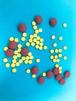 runde mehrfarbige rote und gelbe medizinische pharmazeutische medikamente zur behandlung von krankheiten, die mikroben und viruspillen und vitaminmedikamente gegen coronavirus auf blauem hintergrund abtöten foto