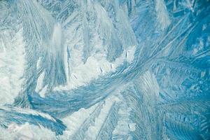 winterliche frostige muster auf glas. weihnachten festlicher hintergrund. glänzende Eiskristalle am Fenster. foto