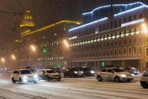 Autos fahren unter Schnee auf der Nachtstraße foto