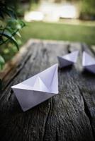 Origami, weißes Papierboot isoliert auf einem Holzboden. Papierboote bedeuten Gehen. Gefühl der Freiheitsführung foto