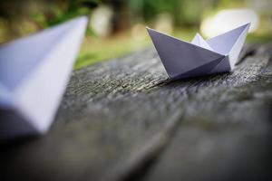 Origami, weißes Papierboot isoliert auf einem Holzboden. Papierboote bedeuten Gehen. Gefühl der Freiheitsführung foto