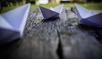 Origami, weißes Papierboot isoliert auf einem Holzboden. Papierboote bedeuten Gehen. Gefühl der Freiheitsführung foto