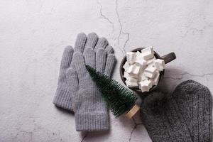 Kakao mit Marshmallows, Wollhandschuhe, Socken und ein Weihnachtsbaum auf Gips. Ansicht von oben. foto