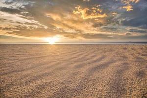 Closeup Sand Textur mit Sonnenuntergang Lichtstrahlen. golden orange sonnenuntergang himmel wolken. mediterrane insellandschaft, ufer tropische küste. entspannender Naturstrand, schöne positive Meditationslandschaft foto