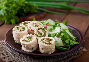 Gedämpfte Hühnerbrötchen mit Gemüse und Salat aus frischem Gemüse auf einer braunen Platte foto