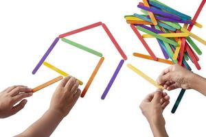 Hand von Kindern, die sich gegenseitig helfen, verbindet die bunten Popsicle-Sticks, die fröhlich auf weißem Hintergrund isoliert sind. foto