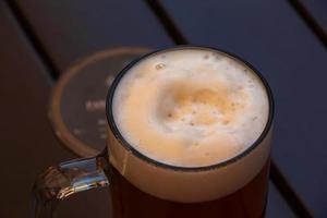 Krug Bier mit weißem, dichtem Schaum auf Holzhintergrund. foto