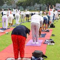 Gruppen-Yoga-Übungssitzung für Menschen verschiedener Altersgruppen im Cricket-Stadion in Delhi am internationalen Yoga-Tag, große Gruppe von Erwachsenen, die an Yoga-Sitzungen teilnehmen foto