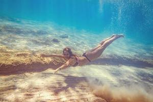 Mädchen, das unter dem Meer schwimmt foto