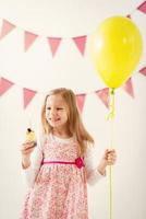 kleines Mädchen mit Ballon und Cupcake foto