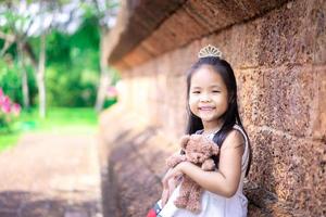 süßes kleines asiatisches Mädchen mit einer Puppe im Park foto