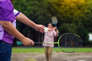 asiatische frau und ihr freund badmintonspieler spielen badminton zusammen nach der arbeit auf dem hof bei der arbeit. Konzept, eine Freizeitbeschäftigung jeden Tag nach der Arbeit, weicher und selektiver Fokus. foto