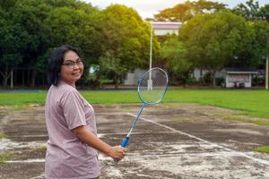 asiatische frau mittleren alters, die einen badmintonschläger hält. Konzept, eine Freizeitbeschäftigung jeden Tag nach der Arbeit, weicher und selektiver Fokus. foto