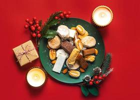 Draufsicht auf Nougat-Weihnachtsbonbon, Mantecados und Polvorones mit Weihnachtsschmuck auf einem Teller. auswahl an weihnachtssüßigkeiten, die typisch für spanien sind foto