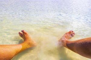 Füße im klaren, türkisfarbenen Wasser auf der Insel Holbox in Mexiko. foto