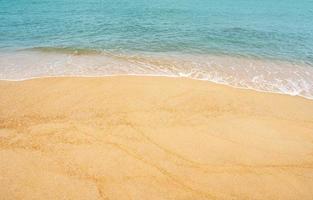 sandstrand und blauer ozean mit weicher wellenform auf sandstruktur, meerblick auf braune strandsanddüne im sonnigen frühlingstag, holizontale draufsicht für sommerbannerhintergrund. foto