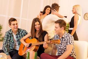 Mädchen spielt Gitarre auf der Hausparty foto