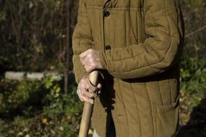 die Hände des alten Mannes. alter Mann mit Stock. schlechte Kleidung. ältere Person arbeitet an Land. foto