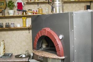 Pizza in der Nähe des Steinofens mit Feuer. Hintergrund eines traditionellen Pizzeria-Restaurants mit Kamin. foto