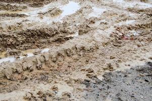 Textur einer schmutzigen, schlechten Schotterstraße Schotterstraße mit Pfützen und trocknendem Lehmschlamm mit Rissen und Furchen. Offroad. der Hintergrund foto