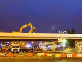 Bau einer Brücke in der Innenstadt. Die Überführung hat Risse und wird nachts repariert. Baumaschinen, Kräne stehen herum foto