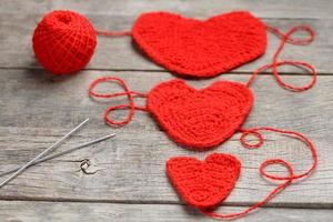 Drei rote gestrickte Herzen auf grauem Holzhintergrund symbolisieren Liebe und Familie. Familienbeziehung, Bindungen. foto