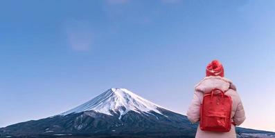 junge rucksackfrau, die auf fuji-berg, rückansicht, reise und urlaub in japan auf winterkonzept schaut. foto