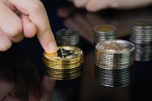 Nahaufnahme des Fingers, der die goldene Bitcoin-Münze berührt foto