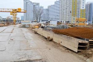 Eine große moderne Baustelle im Bau von Gebäuden und Häusern mit Geräten und vielen großen hohen Türmen und stationären industriellen leistungsstarken Kränen und Baumaterialien foto