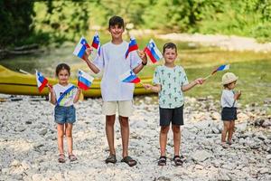 vier kinder halten slowenische fahnen am felsigen ufer eines ruhigen flusses im triglav-nationalpark, slowenien. foto