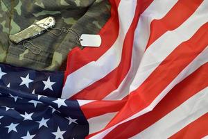 Army Dog Tag Token und Messer liegen auf alter Tarnuniform und gefalteter Flagge der Vereinigten Staaten foto