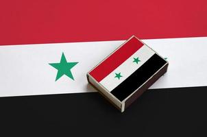 Die syrische Flagge ist auf einer Streichholzschachtel abgebildet, die auf einer großen Flagge liegt foto
