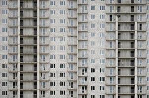 Strukturmuster einer russischen Whitestone-Wohnhauswand mit vielen Fenstern und Balkon im Bau foto